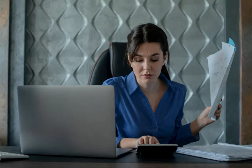 Mulher trabalhando em um notebook sobre uma mesa em ambiente de escritório representando: Notas fiscais e EFD-Reinf: como evitar inconsistências.