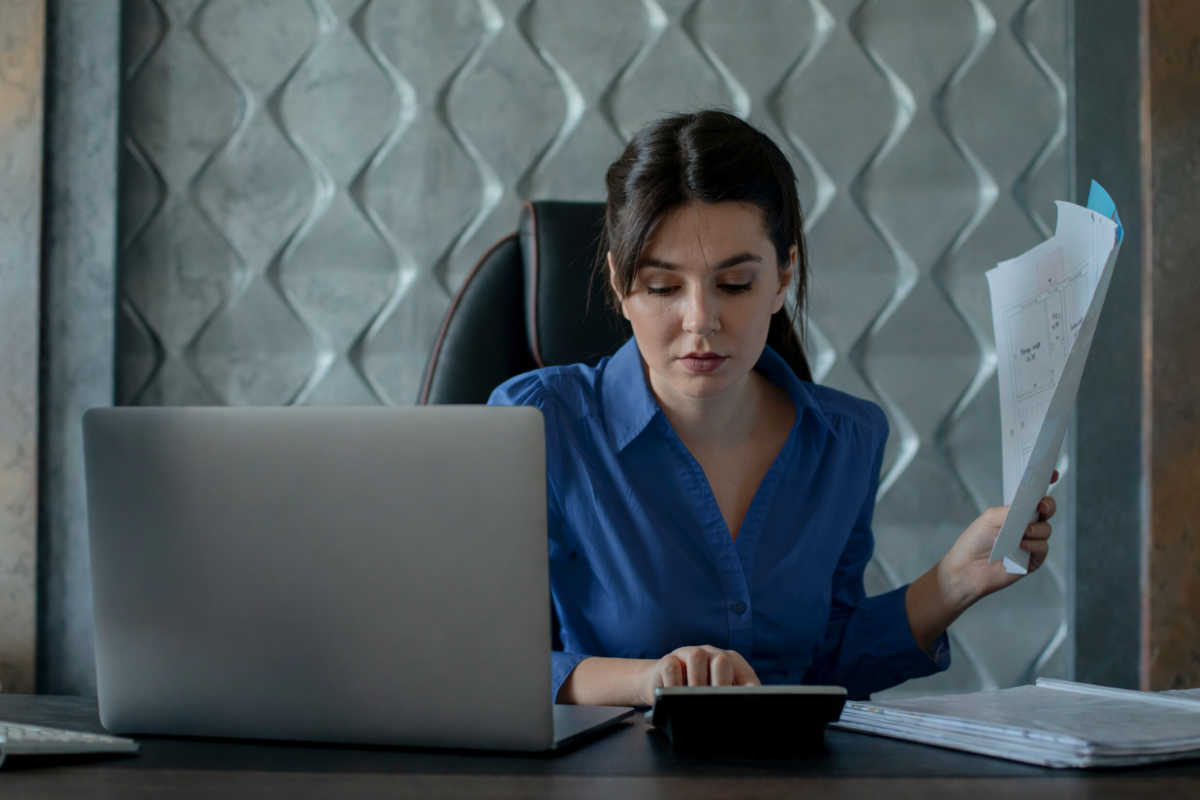 Mulher trabalhando em um notebook sobre uma mesa em ambiente de escritório representando: Notas fiscais e EFD-Reinf: como evitar inconsistências.