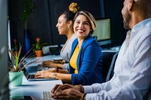 Equipe de contadores e advogados trabalhando em seus computadores e dialogando sobre Como o cadastro de produtos muda a emissão de notas fiscais na Reforma Tributária em ambiente de escritório.