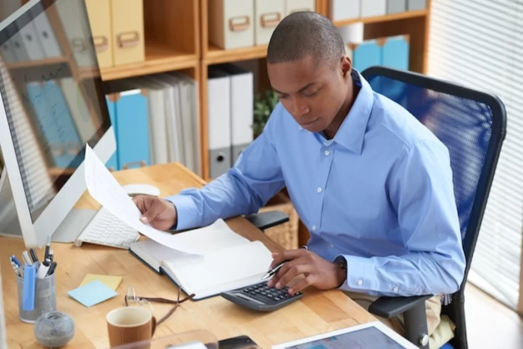 Profissional masculino trabalhando em seu notebook em ambiente de escritório representando: Retenção de IR na nota fiscal de advogado: quando ocorre e como declarar.