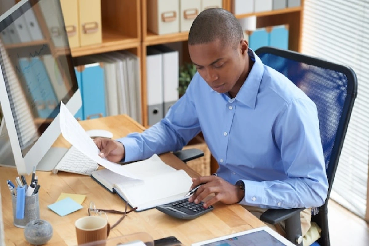 Profissional masculino trabalhando em seu notebook em ambiente de escritório representando: Retenção de IR na nota fiscal de advogado: quando ocorre e como declarar.