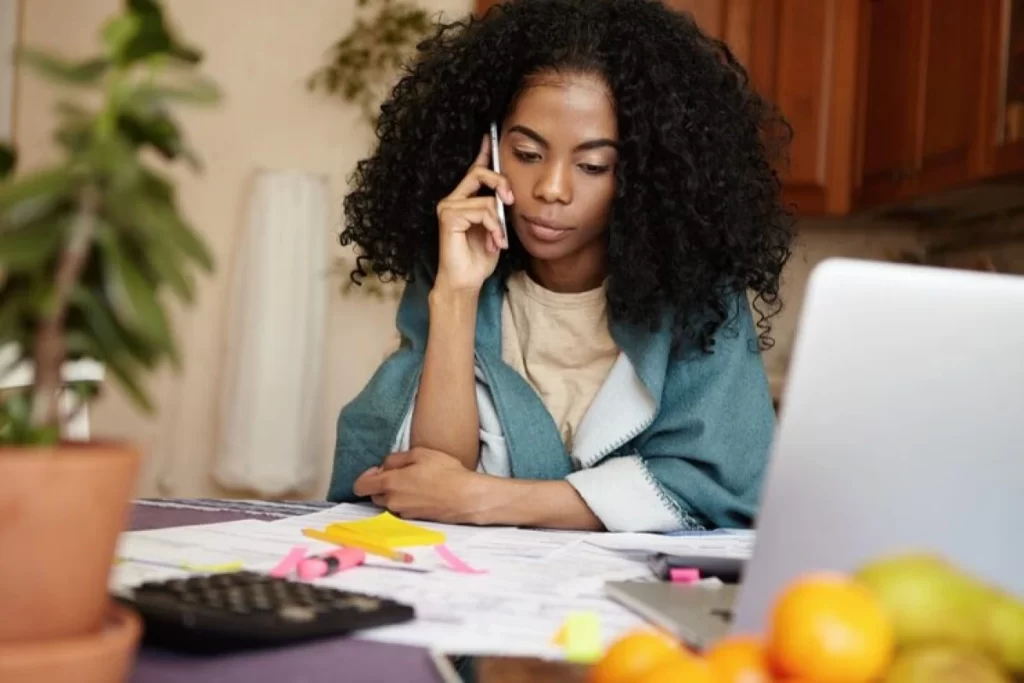 Profissional feminino trabalhando em seu notebook e conversando ao celular representando: Nota fiscal retroativa para advogados: é possível emitir? O que diz a lei