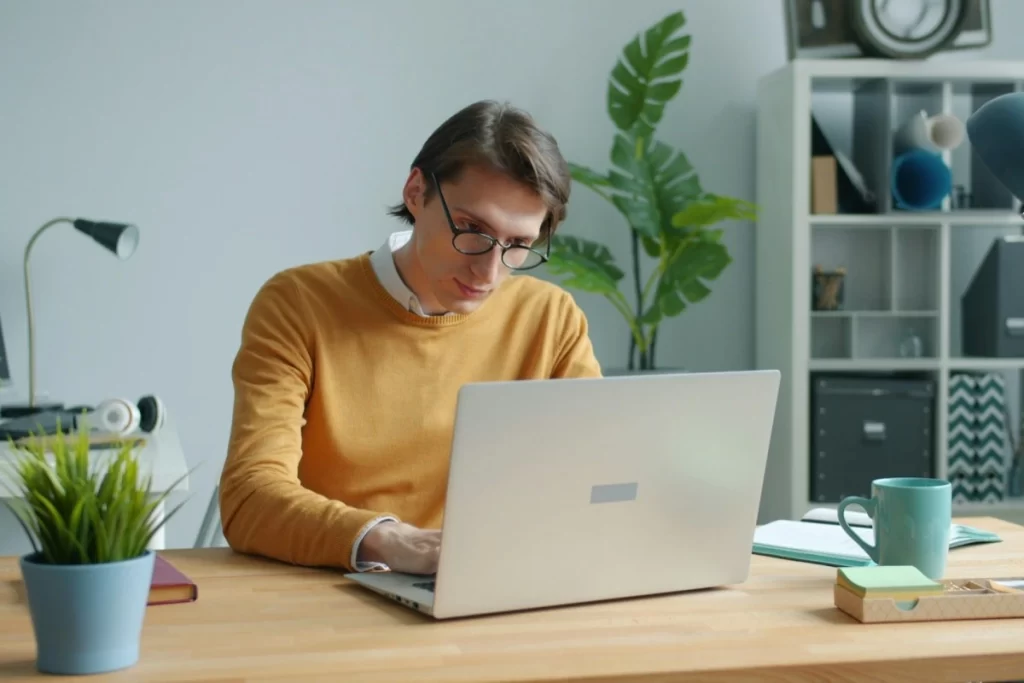 Profissional masculino trabalhando em um notebook sobre Nota fiscal para treino online: como o personal trainer emite para aluno de personal training à distância.