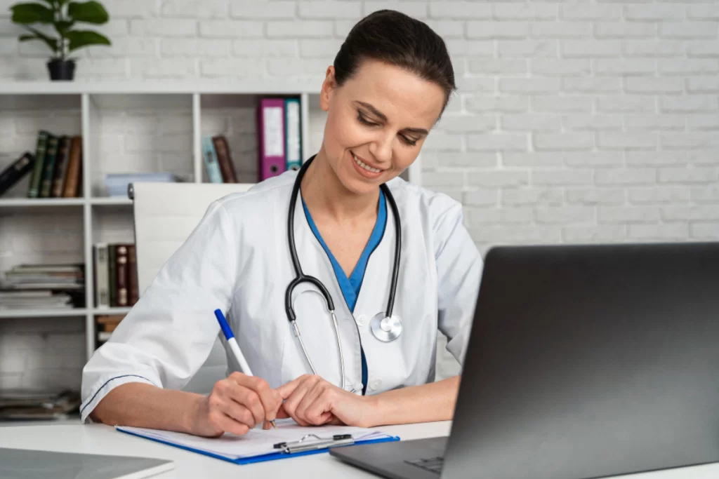 Medica em consultório fazendo receita em sua mesa com um notebook à sua frente representando: Emissor de nota fiscal para médico e psiquiatra: guia completo para consultório e atendimento autônomo