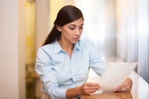 Mulher centada a mesa analisando um folha de papel, representando: Documentação fiscal: o que a empresa precisa guardar