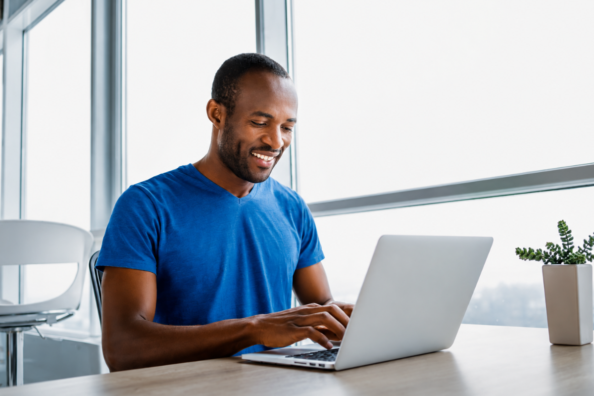 Homem com uma blusa azul em seu escritorio usando notebook, representando: