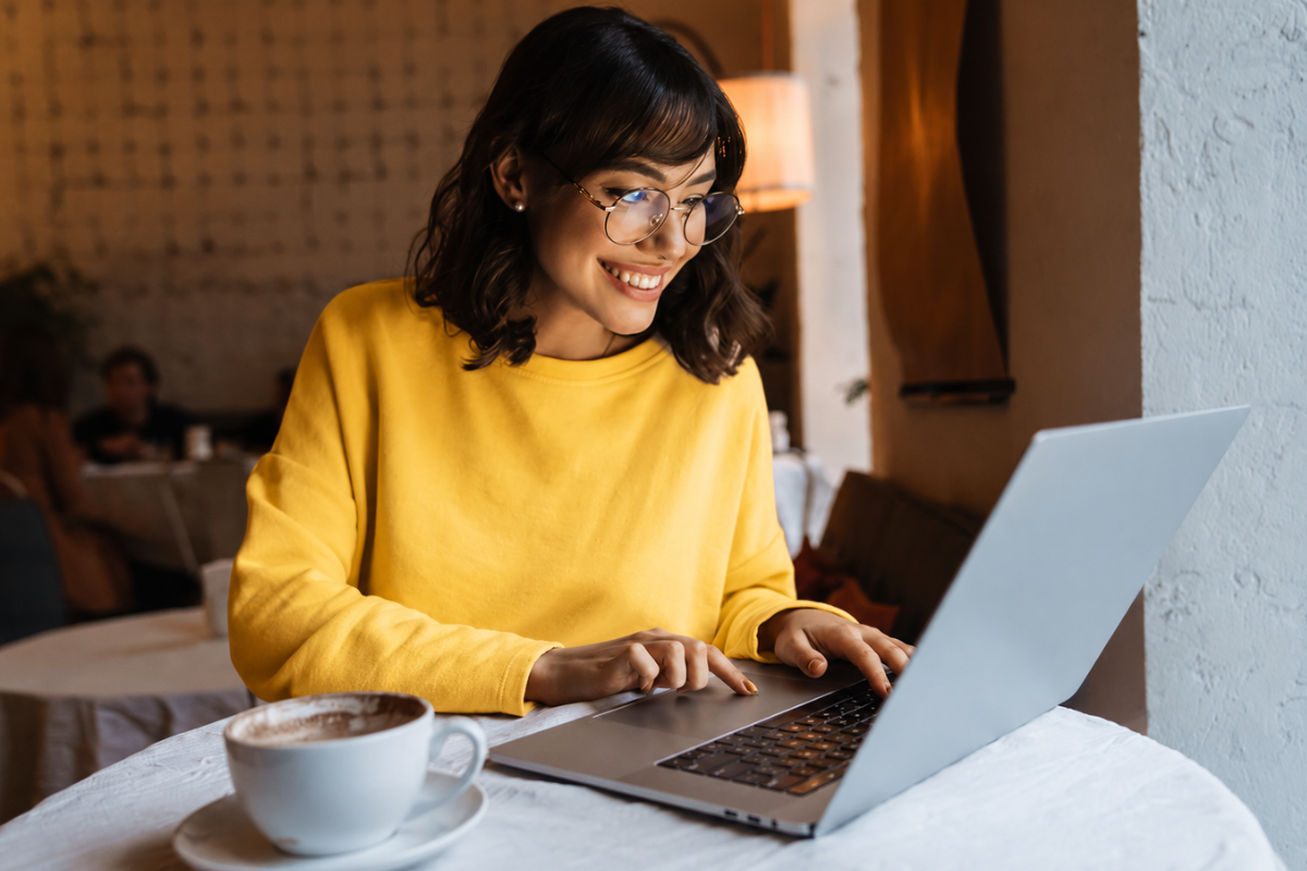 mulher sorridente trabalhando em frete ao seu notebook, representando: Nota fiscal retroativa para advogados